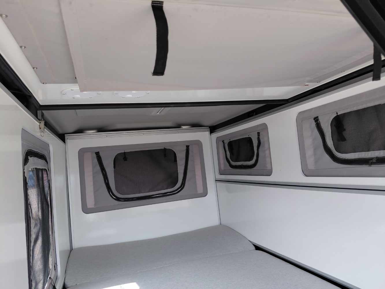 Campervan-Innenraum, Belüftetes Fenster, Seitliches Fenster, Graues Stoffbett, Kompakter Wohnraum,